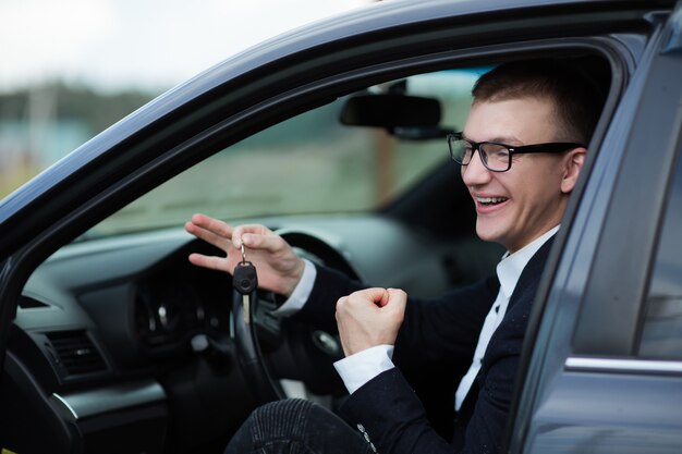 Close up. happy businessman sitting in his new car and showing keys