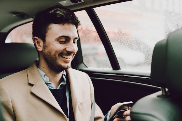 車で旅している間電話を使っている幸せなビジネスマンのクローズアップ