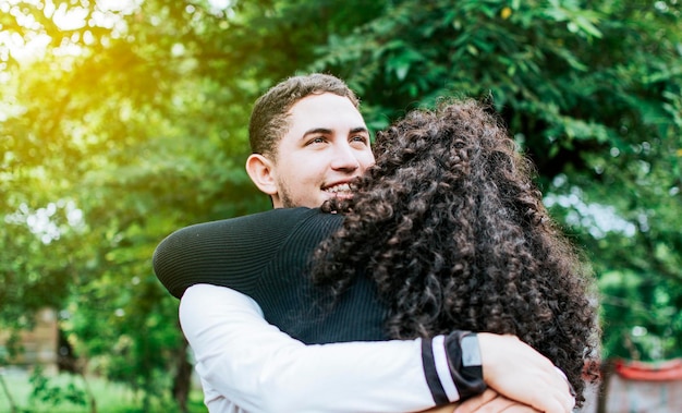 Close up of happy couple hugging in nature Close up of smiling teenage couple hugging Teenage couple hugging outdoors