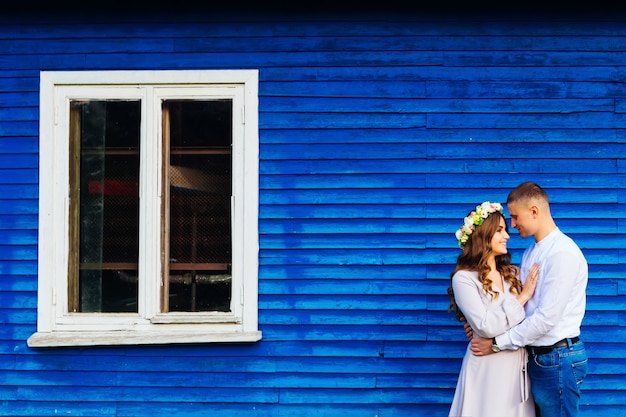 Close-up of a happy couple who smile near a blue house with a white window