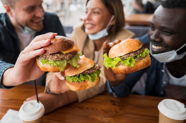 Amici felici del primo piano che tengono gli hamburger