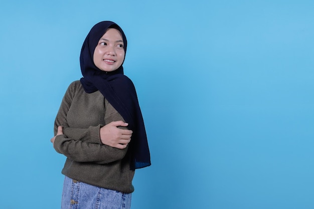 Close-up of happy girl wearing hijab in casual cloth and smiling on blue wall