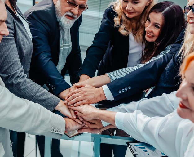 Close up happy group of employees making a stack of hands