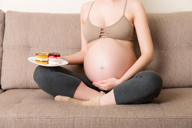 Photo close up of happy hungry woman enjoys eating delicious cakes relaxing at home tasty sweet food during pregnancy concept