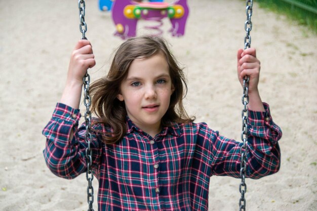 Close up happy little child girl play and sitting on the swing in the nature park