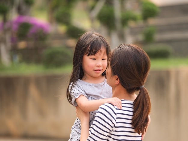 彼女の母親の腕の中で幸せな少女の顔を閉じます。