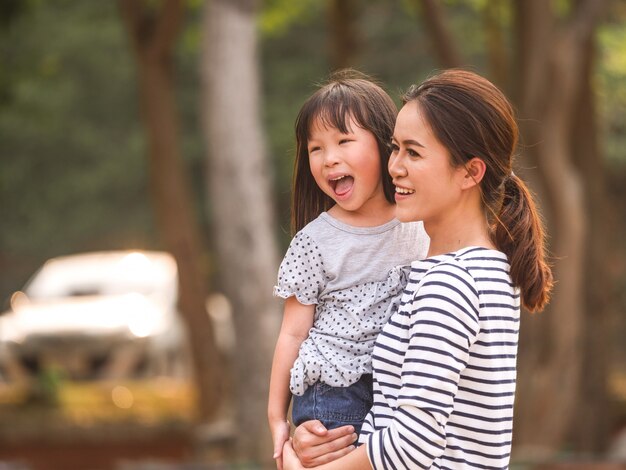 彼女の母親の腕の中で幸せな少女の顔を閉じます。