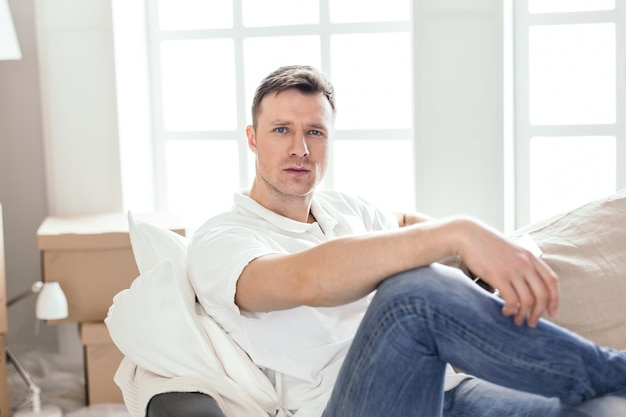 Close up. happy man sitting on the couch in his new apartment