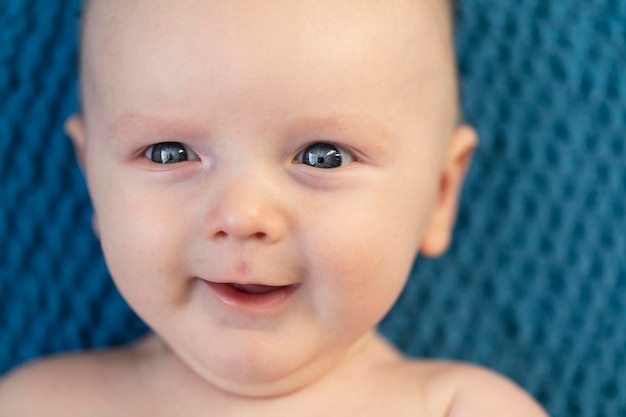 Крупный план счастливого улыбающегося ребенка на фоне голубого одеяла