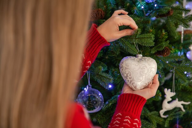 Chiuda in su dell'albero di natale di decorazione della donna felice, concetto delle feste di nuovo anno