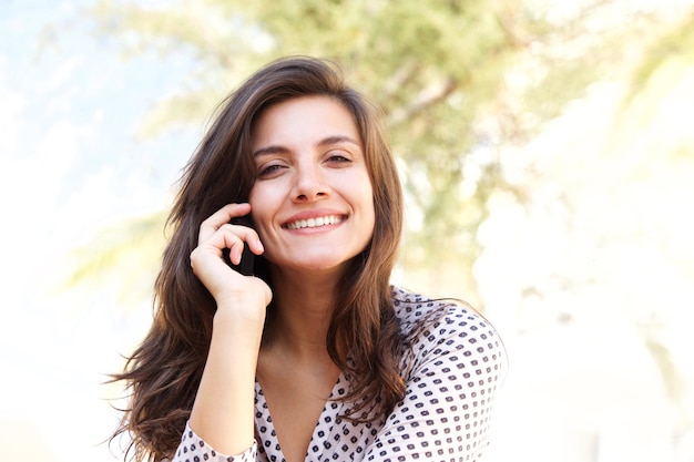 Close up happy woman talking on mobile phone outside