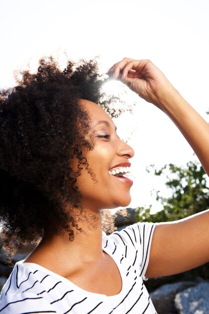 Close up happy young black woman with curly hair smiling outdoors