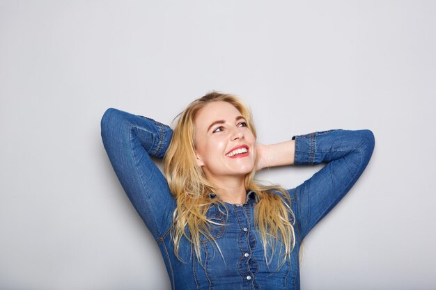 Close up happy young blond woman with hands behind head