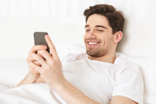 Close up happy young man lying in bed