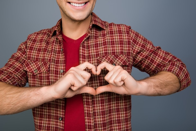 Close up of happy young man making heart with fingers