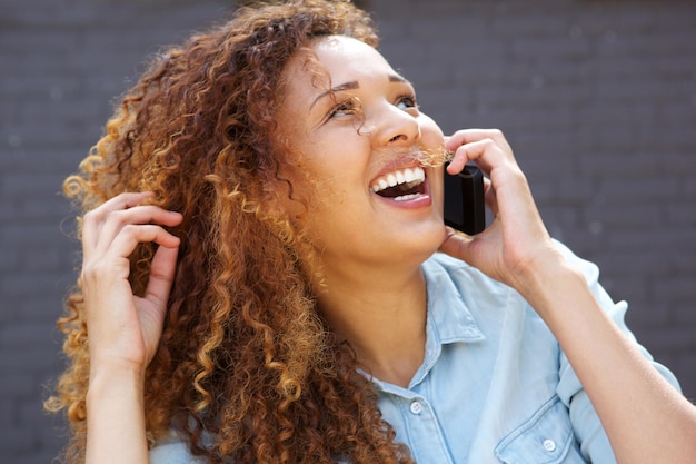 Photo close up happy young woman laughing and talking on mobile phone