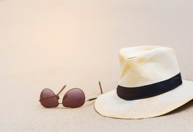 Foto close-up di cappello e occhiali da sole sulla sabbia