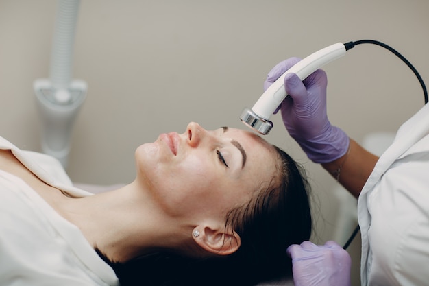 Close up of head woman receiving electroporation phonophoresis facial therapy at beauty spa salon.