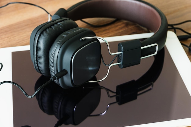 Photo close-up of headphones and digital tablet on table