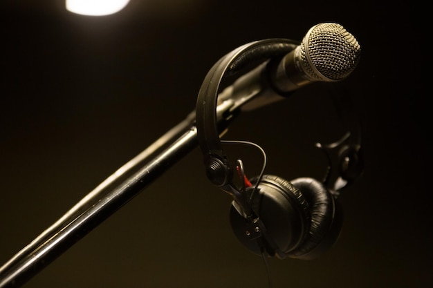 Photo close-up of headphones hanging on microphone in recording studio