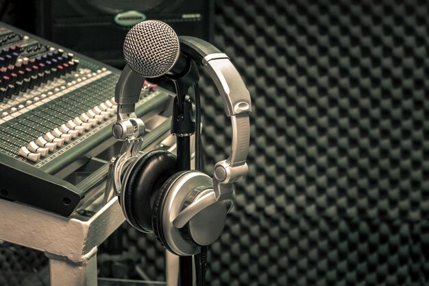 Photo close-up of headphones hanging on microphone stand at recording studio