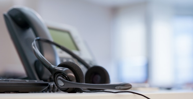 Foto chiuda su sulla call center dell'auricolare con il telefono al concetto della sala operatoria del monitoraggio dell'ufficio