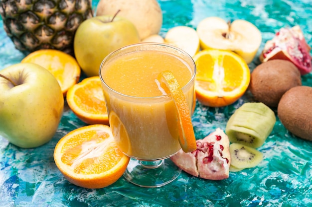 Close up of healthy and fresh fruits next to glass with detox juice on wooden background