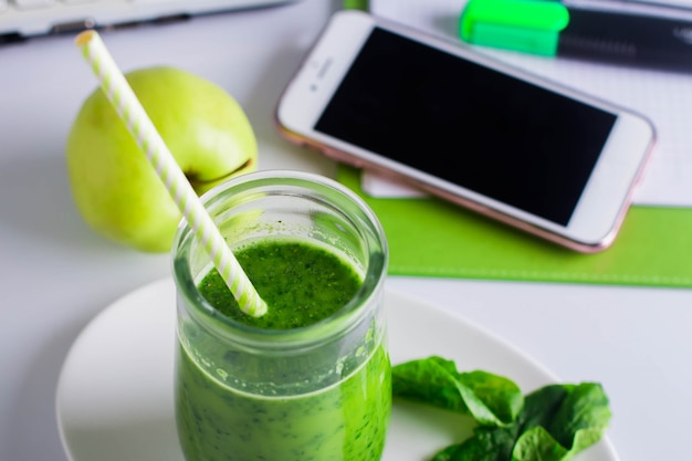 Close up of Healthy Green Smoothie on Workplace working table with notebook