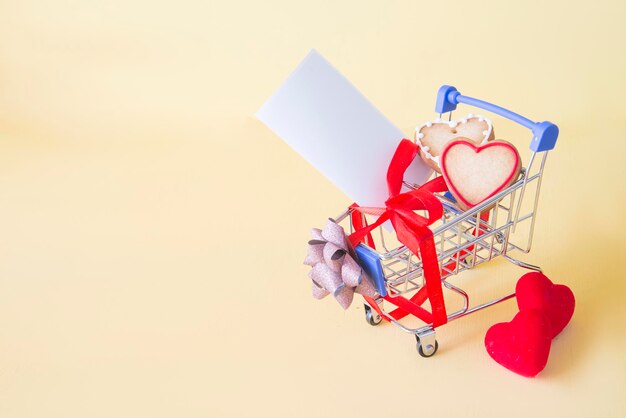 Close-up of heart shape cookies in small shopping cart against yellow background