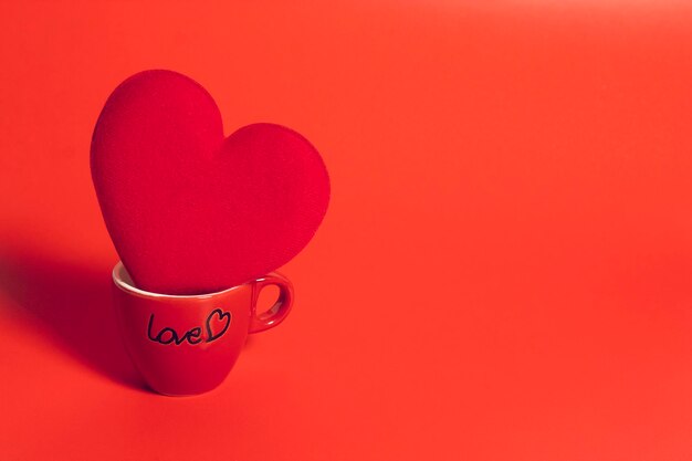 Close-up of heart shape in cup against red background