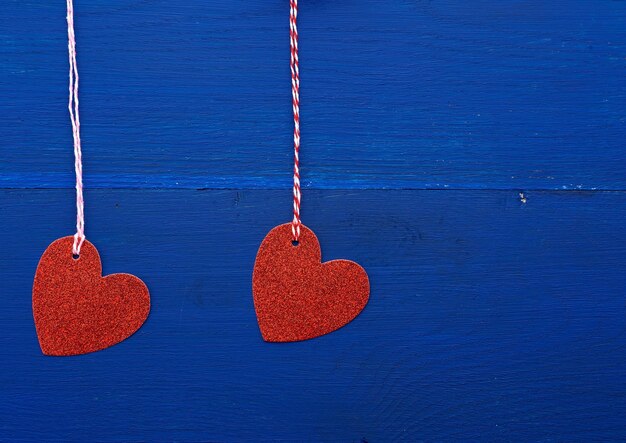 Close-up of heart shape hanging on rope against blue wall