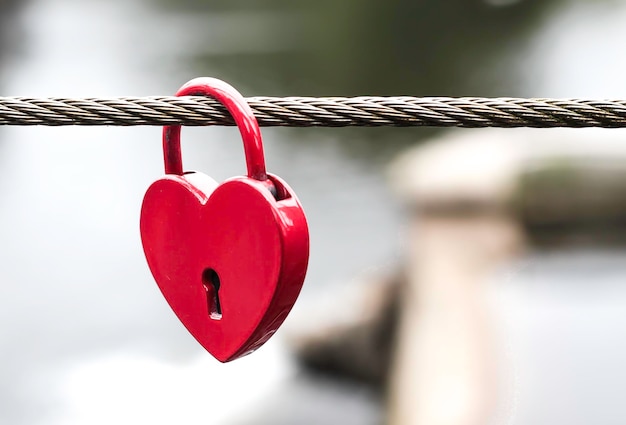 Foto close-up di una serratura d'amore a forma di cuore appesa a una corda