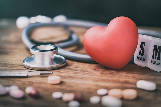 Foto close-up della forma del cuore e della medicina con lo stetoscopio sul tavolo