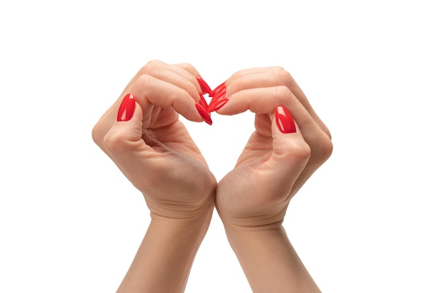 Close up of heart symbol made by woman hands with red nails isolated on white background