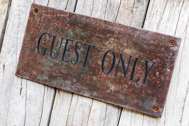 Foto close-up het woord gast alleen geschilderd op oud roestig staal op oude houten deur