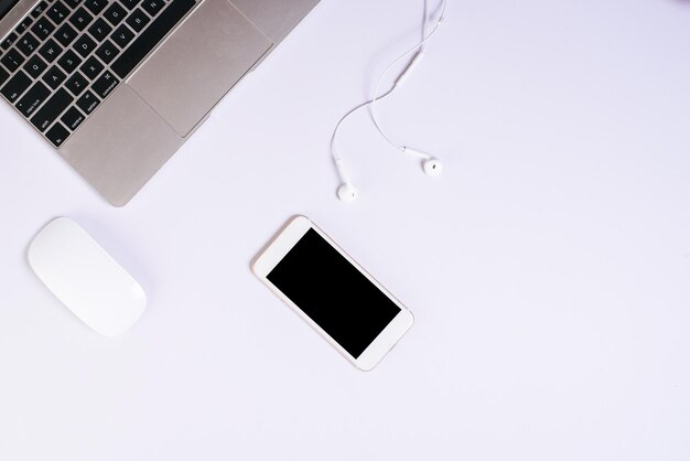 Фото Близкий вид ноутбука с смартфоном и наушниками на белом фоне