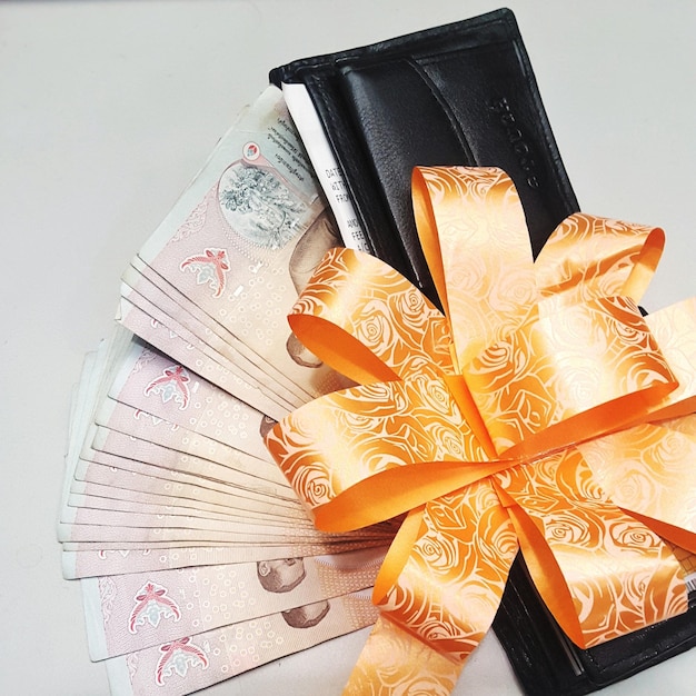 Close-up high angle view of paper currency with wallet and ribbon on table