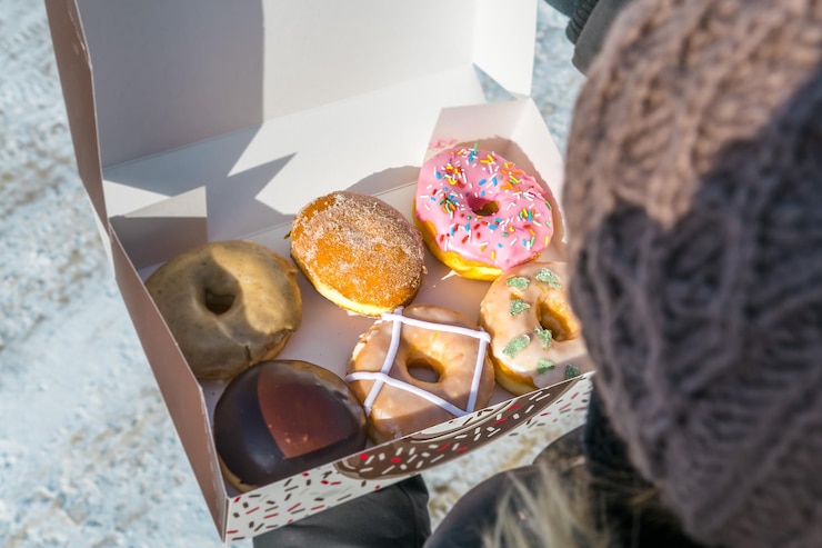 Photo close-up high angle view of woman holding various donuts in box