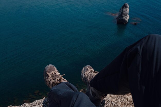 Close up of hiking boots of an independent male traveler on top of a mountain looking at the view