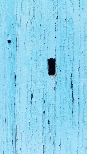 Close-up of hole in blue wooden wall