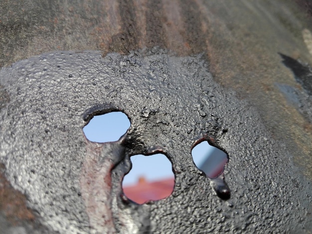 close-up of holes in rusty metal against sky