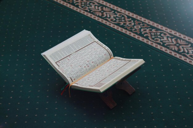 Photo a close up of the holy book alquran on a green prayer rug islamic photo concept