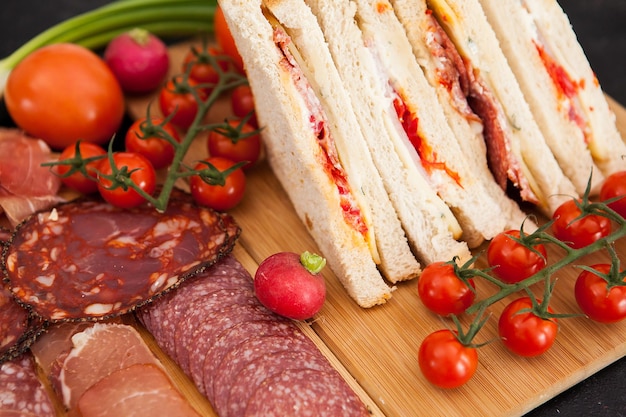 Close up of home made club sandwiches next to a board with appetizers