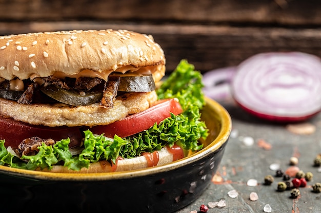 Крупный план домашнего вкусного гамбургера с курицей, солеными огурцами и жареным луком на деревянном столе. концепция быстрого питания и нездорового питания