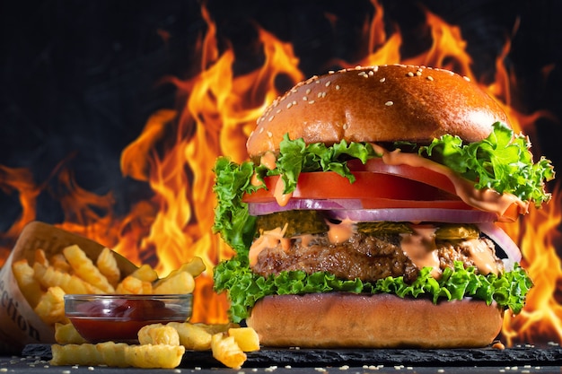 Primo piano di gustosi hamburger fatti in casa con patatine fritte e fiamme di fuoco.