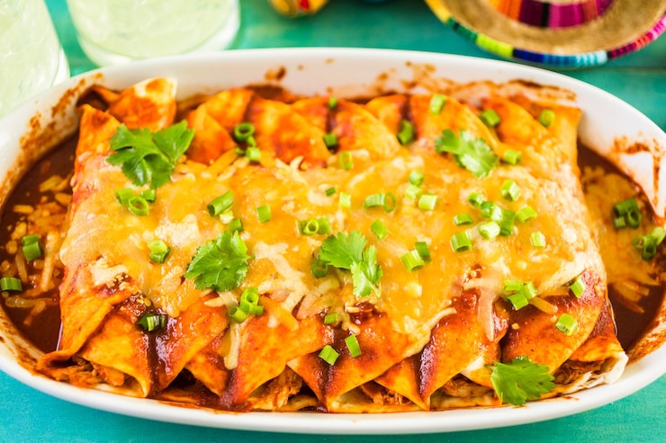 Photo close up of homemade chicken enchiladas garnished with green onion and cilantro.
