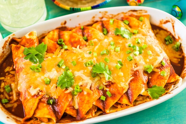 Close up of homemade chicken enchiladas garnished with green onion and cilantro.