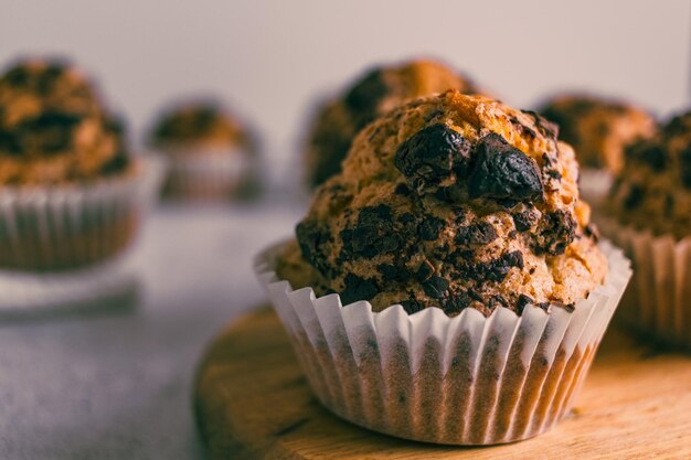 Close up of homemade muffin with chocolate chips on wood cutting board.