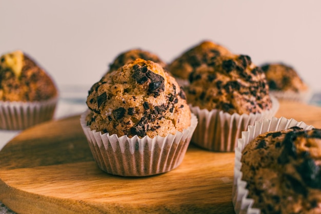 Close up of homemade muffin with chocolate chips on wood cutting board.