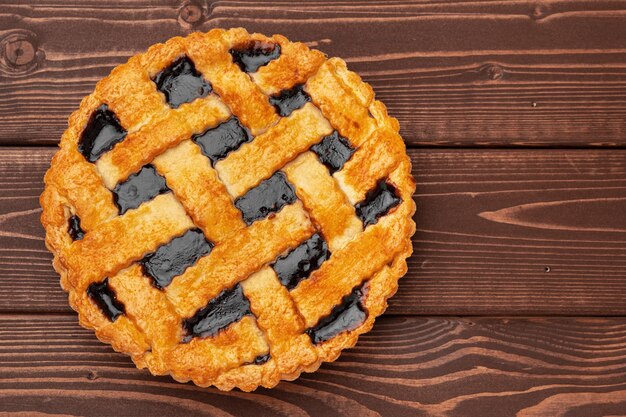 Close up of homemade traditional sweet autumn raspberry tart pie on wooden table